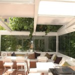 Cerramiento de establecimiento con terraza: techo móvil de policarbonato y cortina de cristal.